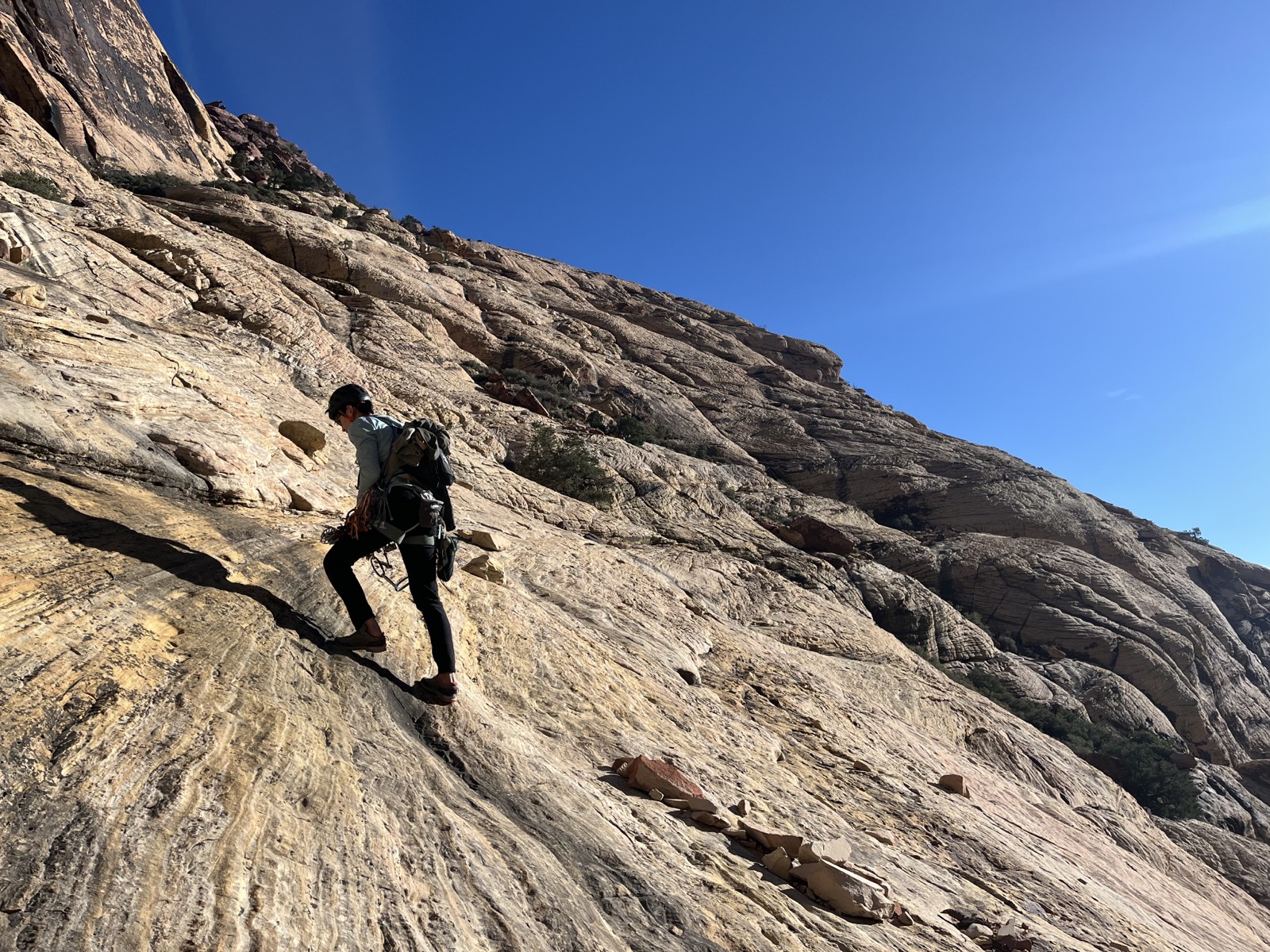 A climber scrambling up sandstone slabs on the approach to Brownstone Wall at Red Rock