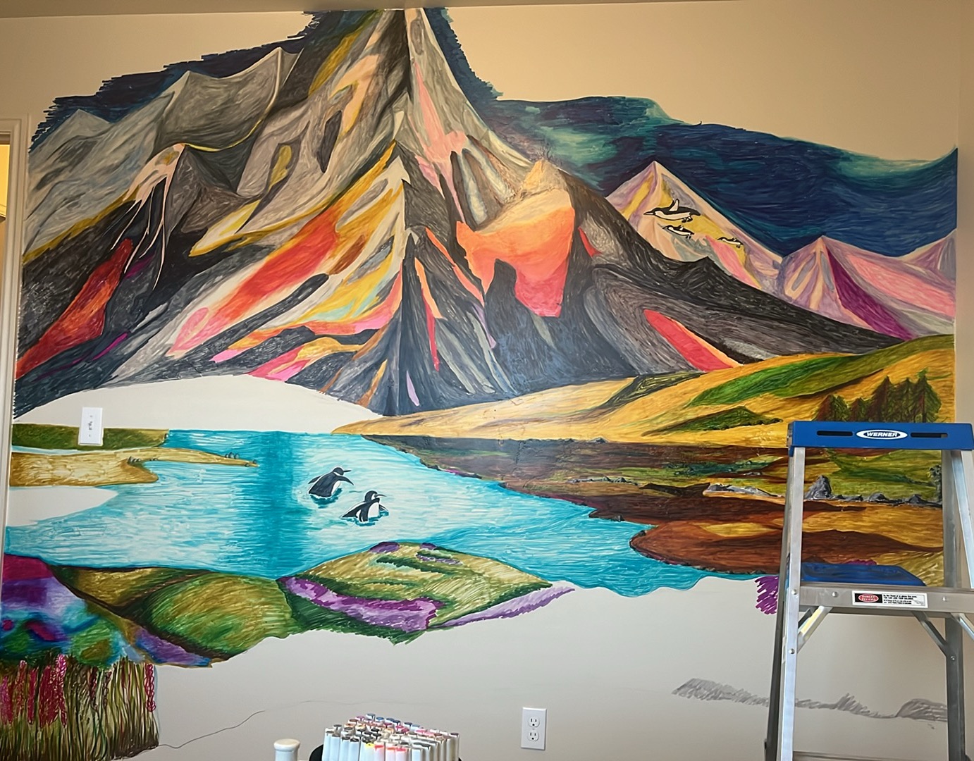A hand-drawn marker mural of a colorful mountain range above a turquoise lake